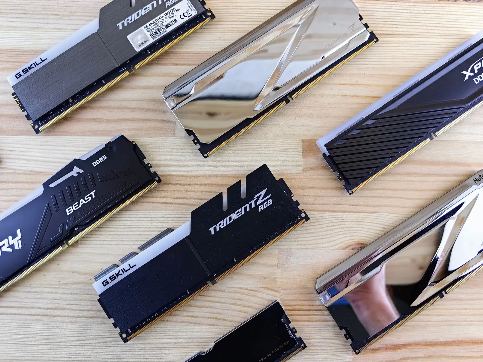 Various DDR4 and DDR5 desktop RAM modules from G.Skill and XPG on a wooden surface