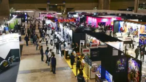 Widok z góry na halę targową Tokyo Game Show z tłumem ludzi i stoiskami firm Konami oraz Sega Atlus
