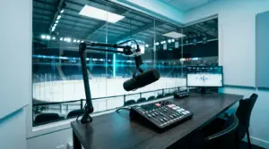 Mikrofon komentatora przy konsoli audio na tle lodowiska, symbolizujący AI w komentarzu NHL 27