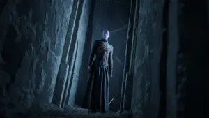 Postać z gry Hellraiser: Revival stojąca w mrocznym, kamiennym korytarzu.